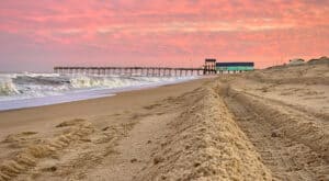Coral sunset over the turquoise pier house at Avalon Pier in Kill Devil Hills, North Carolina.