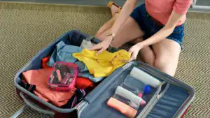 cropped view of girl sitting on floor and packing baggage