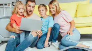 happy family using laptop planning summer vacation packing luggage and