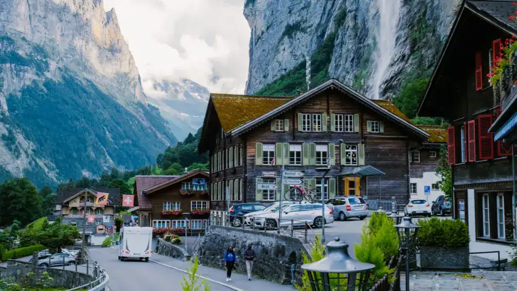 Charming village houses in Lauterbrunnen Valley, Switzerland, with the Staubbach Falls cascading down the cliffs in the background.