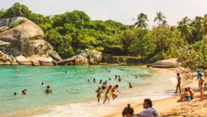 people in caribbean beach with tropical forest in tayrona nation