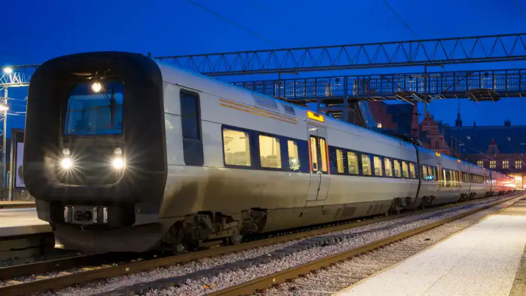 Modern night train arriving at a station under a deep blue evening sky