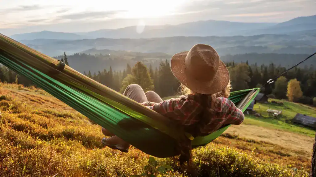 Woman hiker resting in a hammock at sunset after climbing 